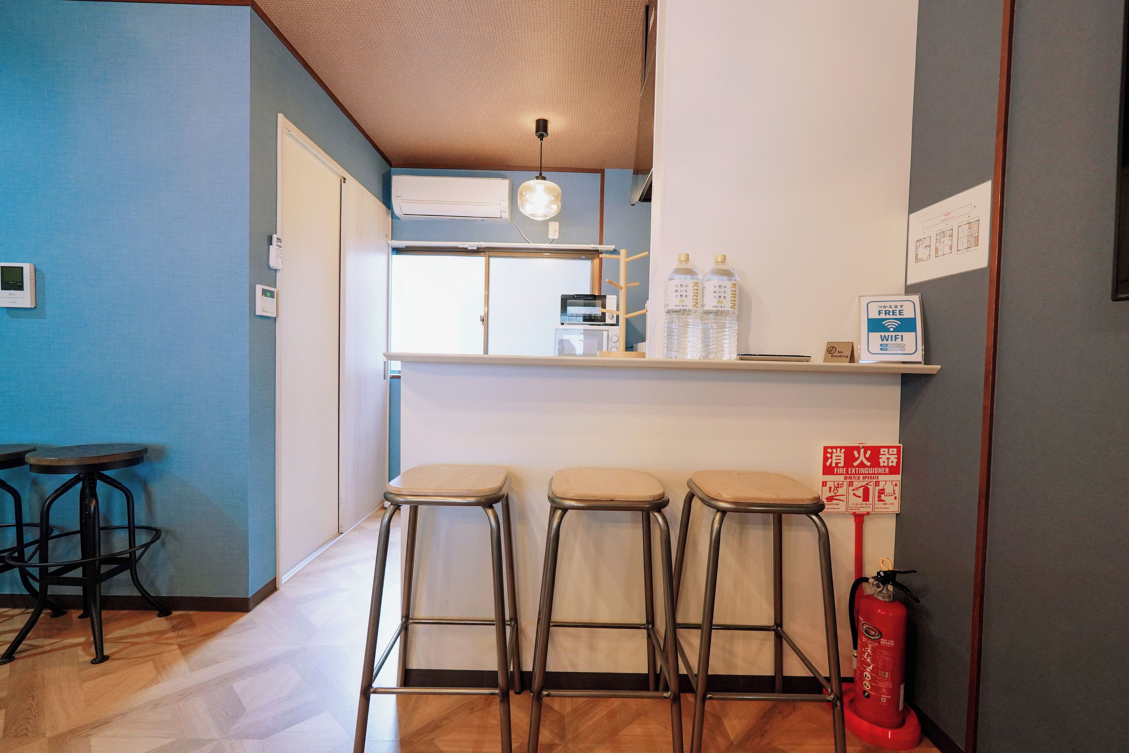 Zona de bar con taburetes, extintor y señalización de wifi gratuito.