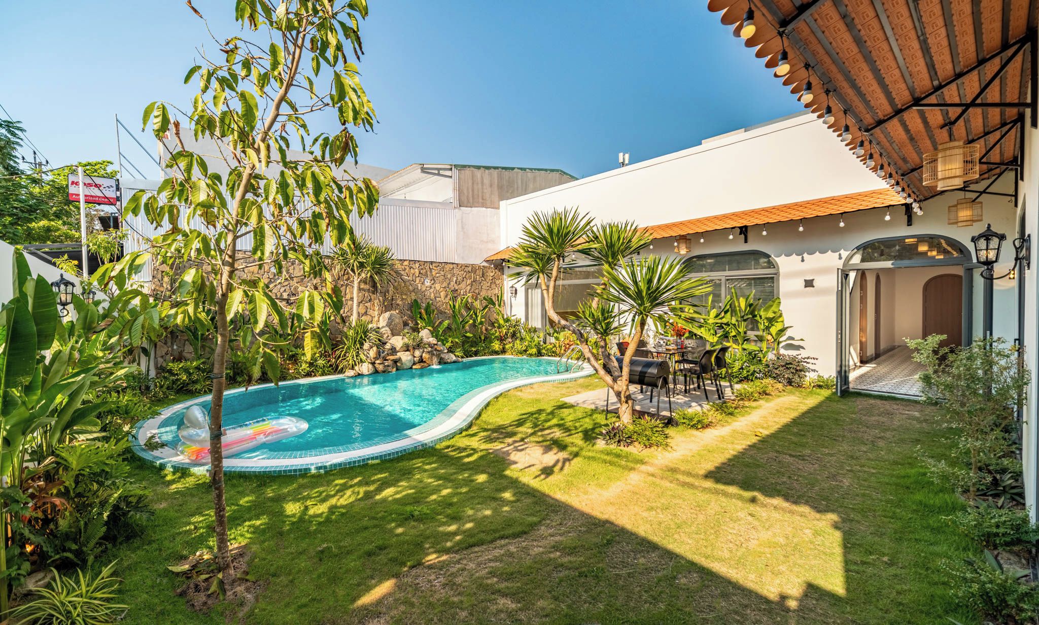 Um imóvel residencial com piscina, muro de pedra e área de varanda.