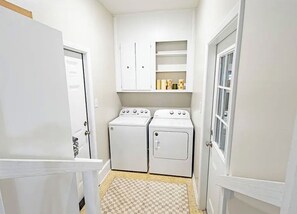 A laundry room with two washing machines and a dryer, a checkered floor, and white walls. - 3-bedroom house in delightful Valdosta with pool, jacuzzi, and cool AC. (Valdosta)