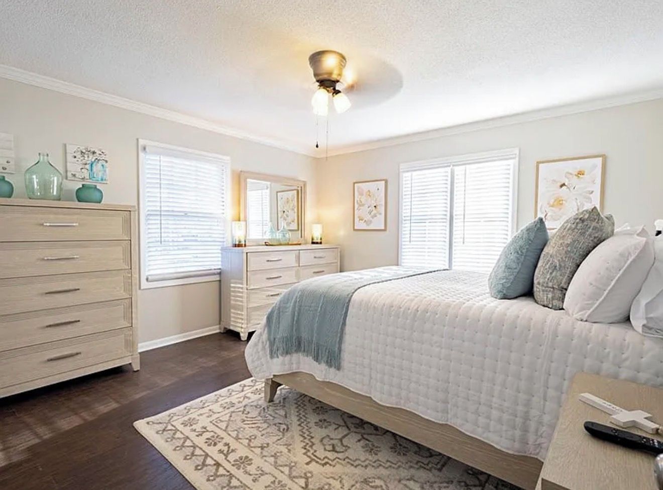 A bedroom with a bed, dresser, nightstand, and a ceiling fan.