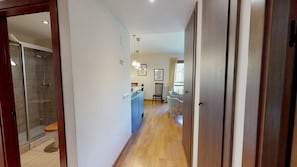 A hallway leading to a bathroom with a shower, a dining area with a table and chairs, and a kitchen area with a counter and cabinets. - Pondiellos 34 - tucasaenlospirineos (Escarrilla)