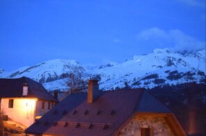 Een besneeuwd berglandschap in de schemering, met een verlicht gebouw op de voorgrond.