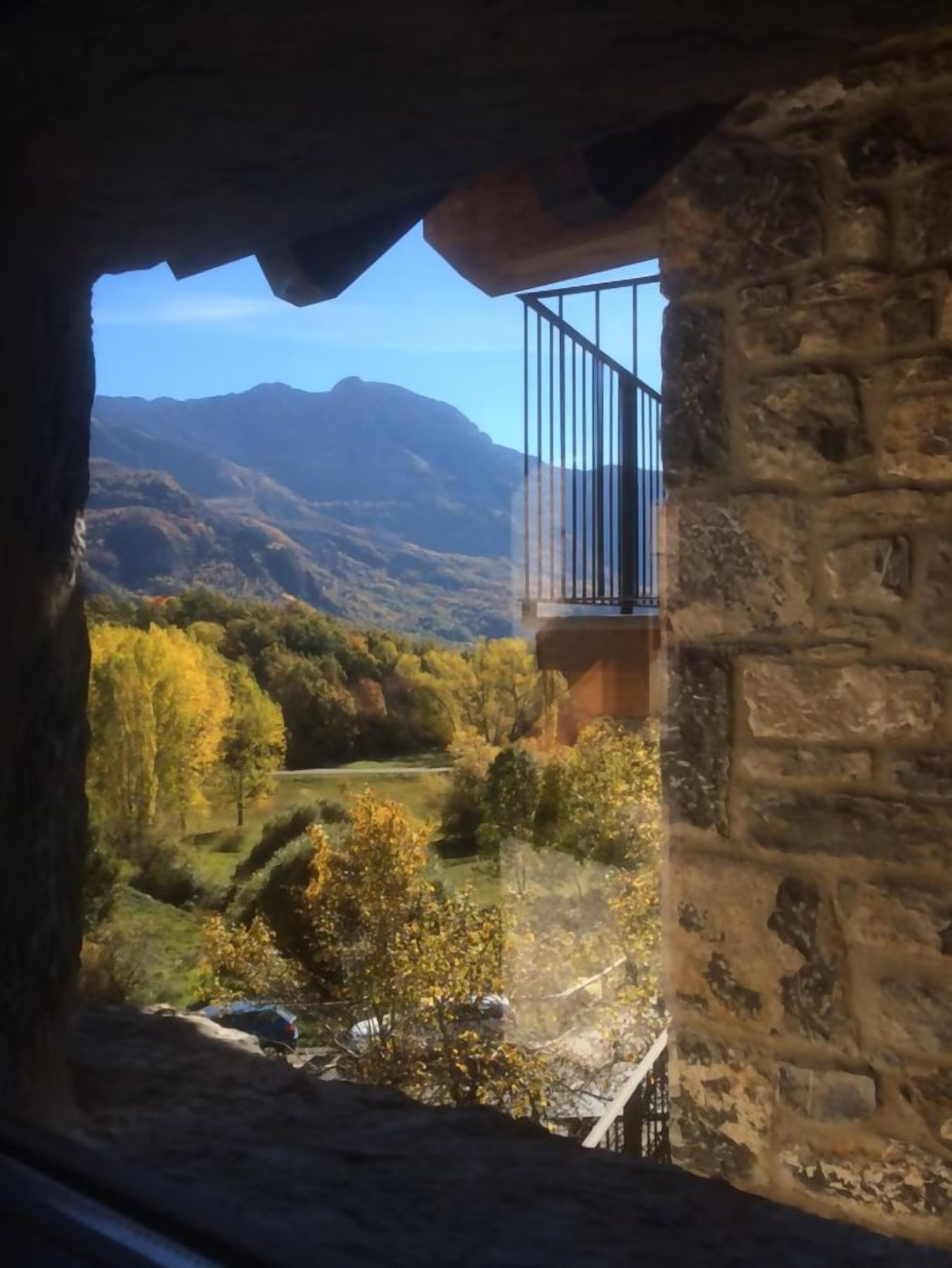 Ein Steinhäuschen mit einem Balkon mit Blick auf eine gebirgige Landschaft.