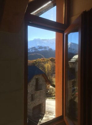 A window with a view of a mountainous landscape and a building with a blue roof. - El Pajar de la Leña - tucasaenlospirineos (Sandinies)