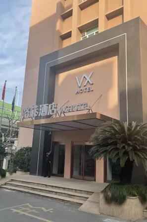 A hotel entrance with a modern design, featuring a prominent logo and signage.
