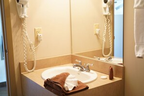 Une salle de bain équipée d’un lavabo, de deux miroirs, d’une serviette et d’un sèche-cheveux.