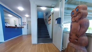 A reception area with a wooden floor, a reception desk, a staircase, and a decorative sculpture.