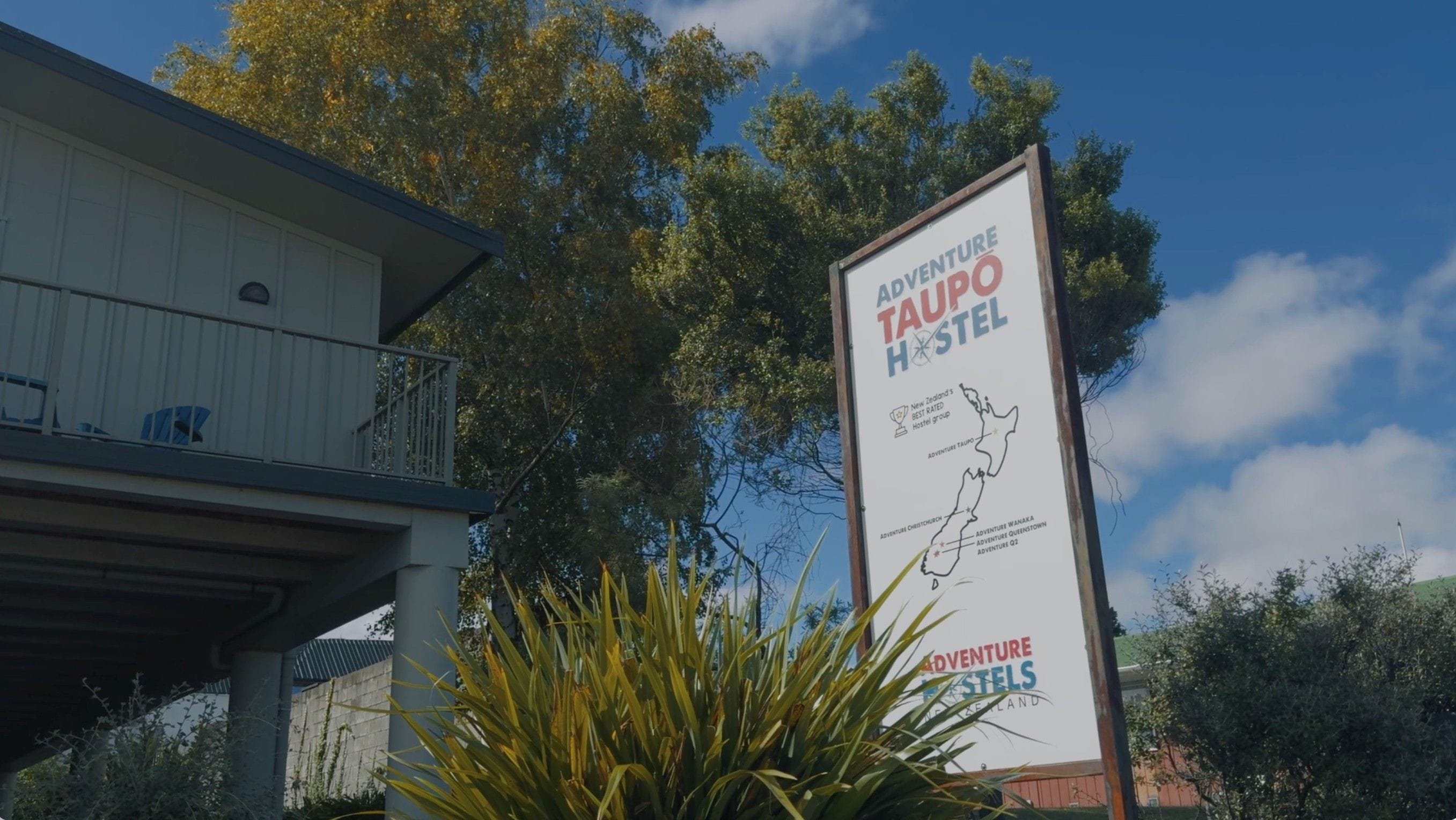 A hostel signboard with a map and text indicating its location in New Zealand.