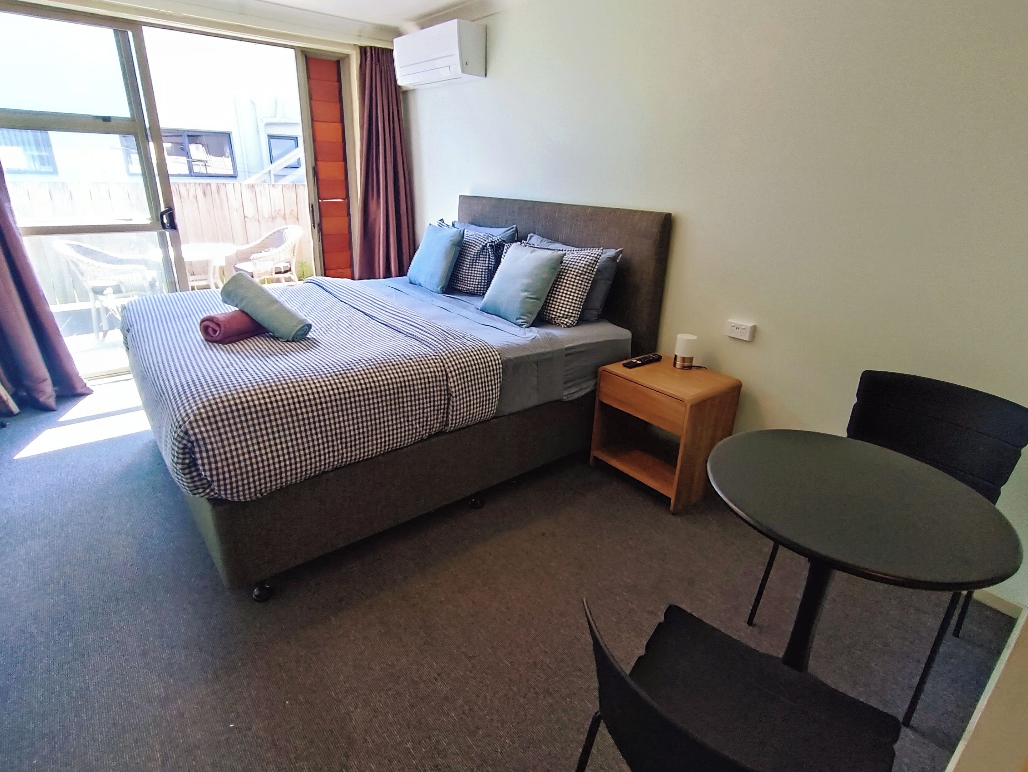 A hotel room with a bed, a nightstand, a table, and a chair.
