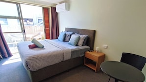 A hotel room with a bed, a nightstand, a table, and a chair.
