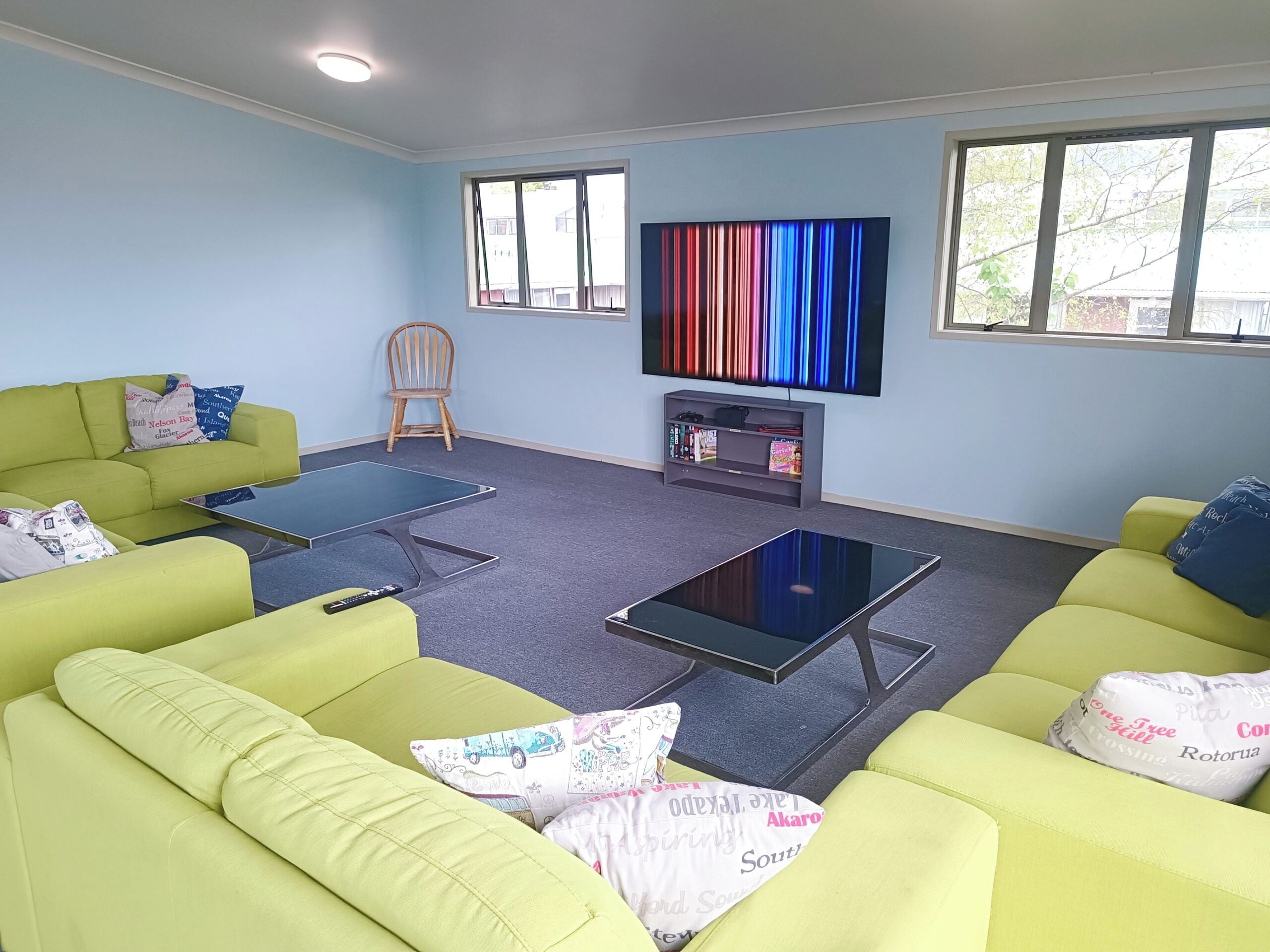 A living room with green sofas, a flat-screen TV, and a bookshelf.