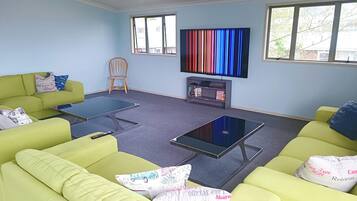 A living room with green sofas, a flat-screen TV, and a bookshelf.