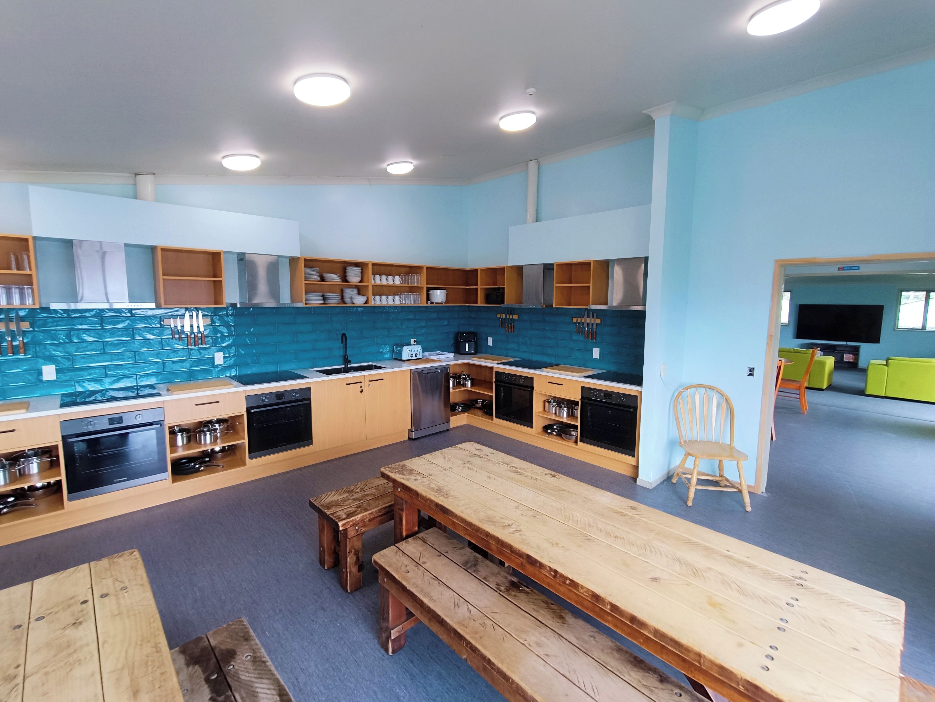 A modern kitchen with built-in appliances, wooden cabinets, and a dining area with a bench.