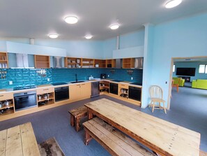 A modern kitchen with built-in appliances, wooden cabinets, and a dining area with a bench.
