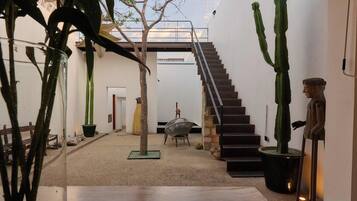 Een modern interieur met een trap naar een hoger gelegen niveau, omringd door potplanten en minimalistische decoratie.