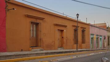 Un edificio con fachada plana, grandes ventanales con barrotes de metal y una bordillo amarillo.