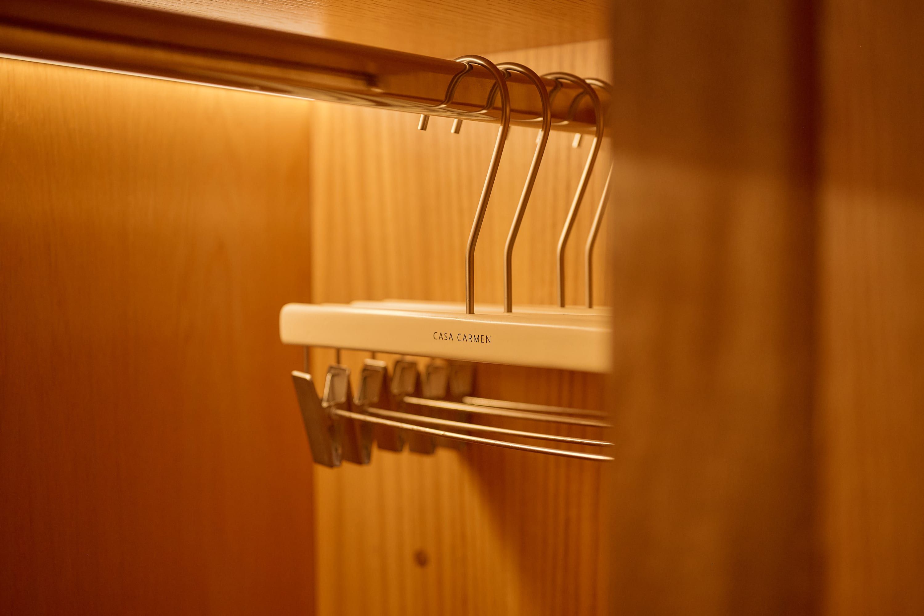 Un intérieur en bois avec un présentoir métallique blanc muni de plusieurs porte-manteaux.