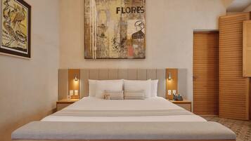 Een hotelkamer met een groot bed, twee nachtkastjes met lampen, een houten garderobe en een schilderij aan de muur.