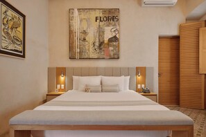 Een hotelkamer met een groot bed, twee nachtkastjes met lampen, een houten garderobe en een schilderij aan de muur.