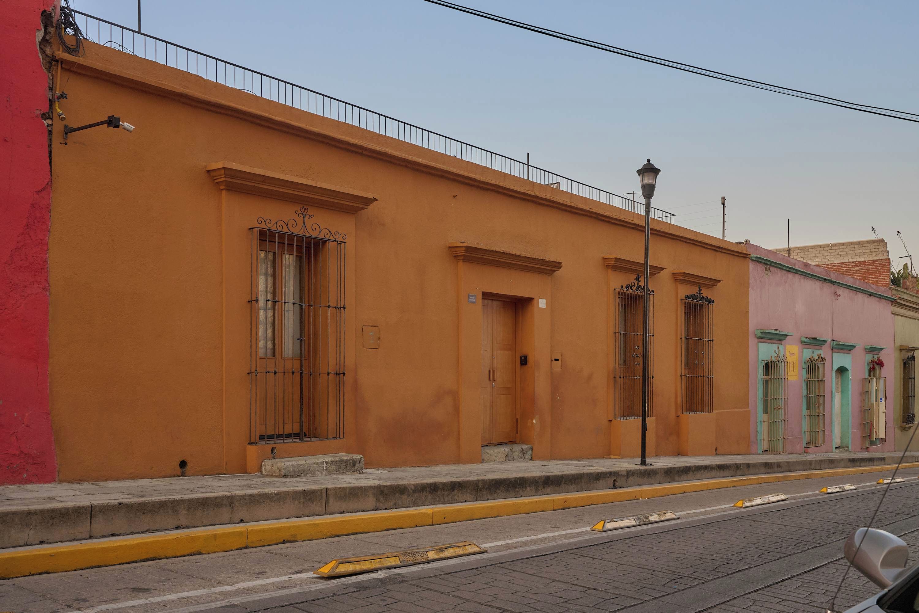 A building with a flat facade, large windows with metal bars, and a yellow curb.