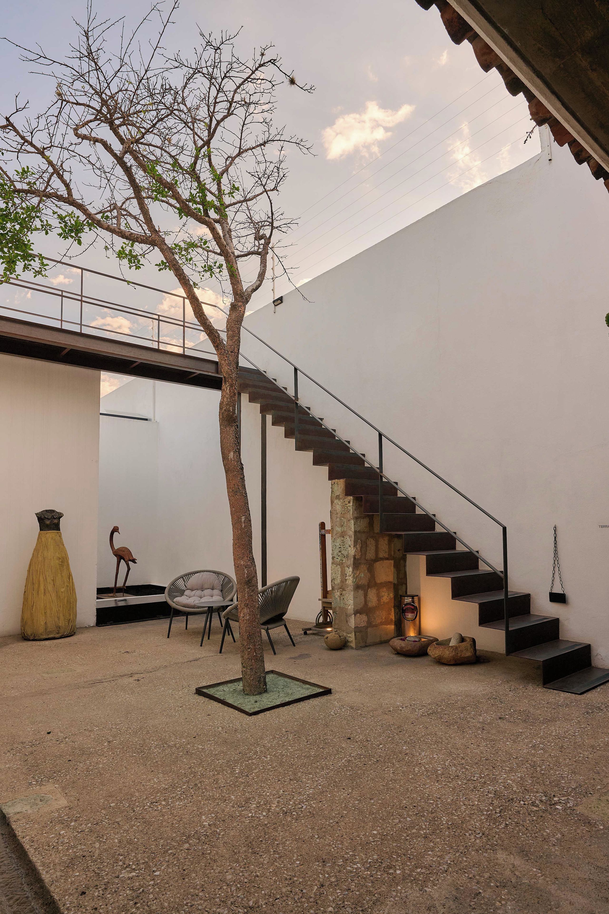A modern outdoor space with a staircase, seating area, and a tree.