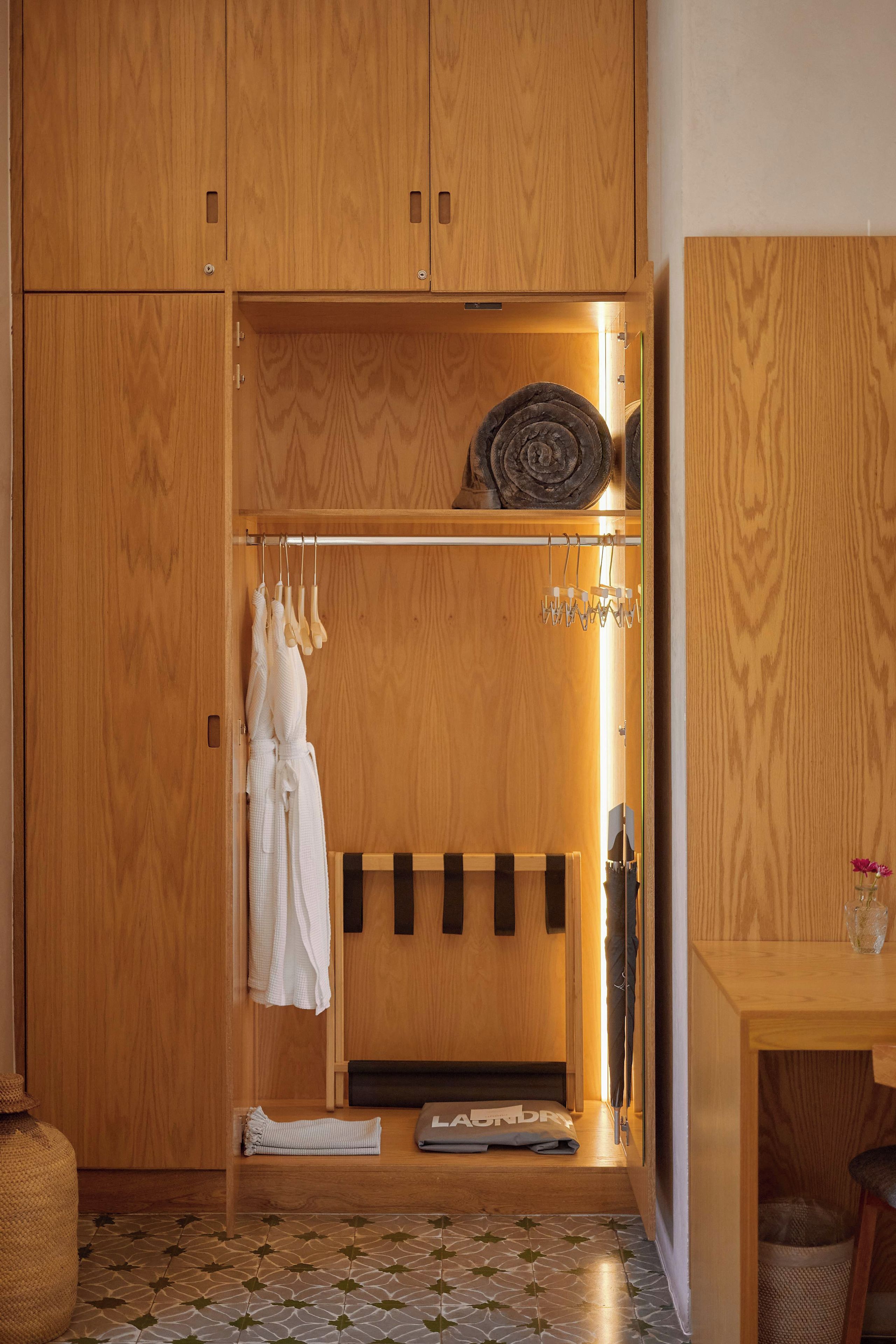 A wooden wardrobe with a hanging rack, a mirror, and a small table with a vase.