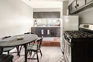 A kitchen with a stove, refrigerator, and dark cabinets.
