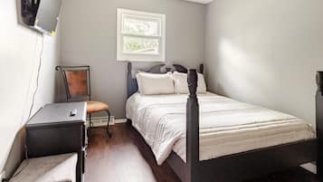 Un dormitorio con cama, escritorio, silla y ventana.