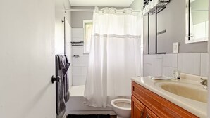 Un baño con bañera, inodoro y tocador con lavabo.