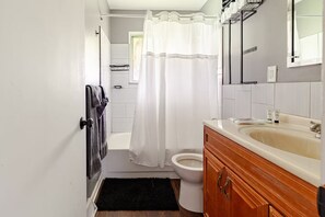 A bathroom with a bathtub, toilet, and vanity with a sink.