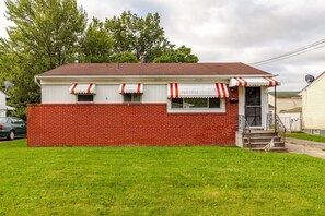 A single-story house with a brick exterior, a red and white awning, and a small front porch with steps.