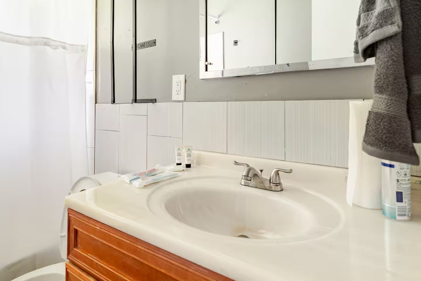Une salle de bain avec un lavabo blanc, un porte-serviettes et des articles de toilette posés sur le comptoir.