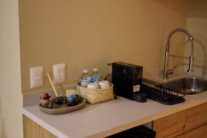 A kitchen counter with a coffee maker, a sink, and various kitchen items. - Vibrant Oaxaca Suites Steps from Santo Domingo (Oaxaca de Juárez)