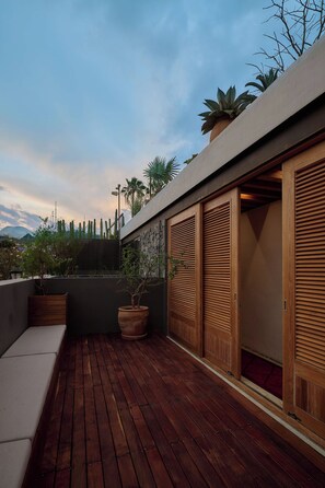 A wooden deck with potted plants, a stone wall, and a view of the sky. - Artistic Oasis in Oaxaca's Historic Center (Oaxaca de Juárez)