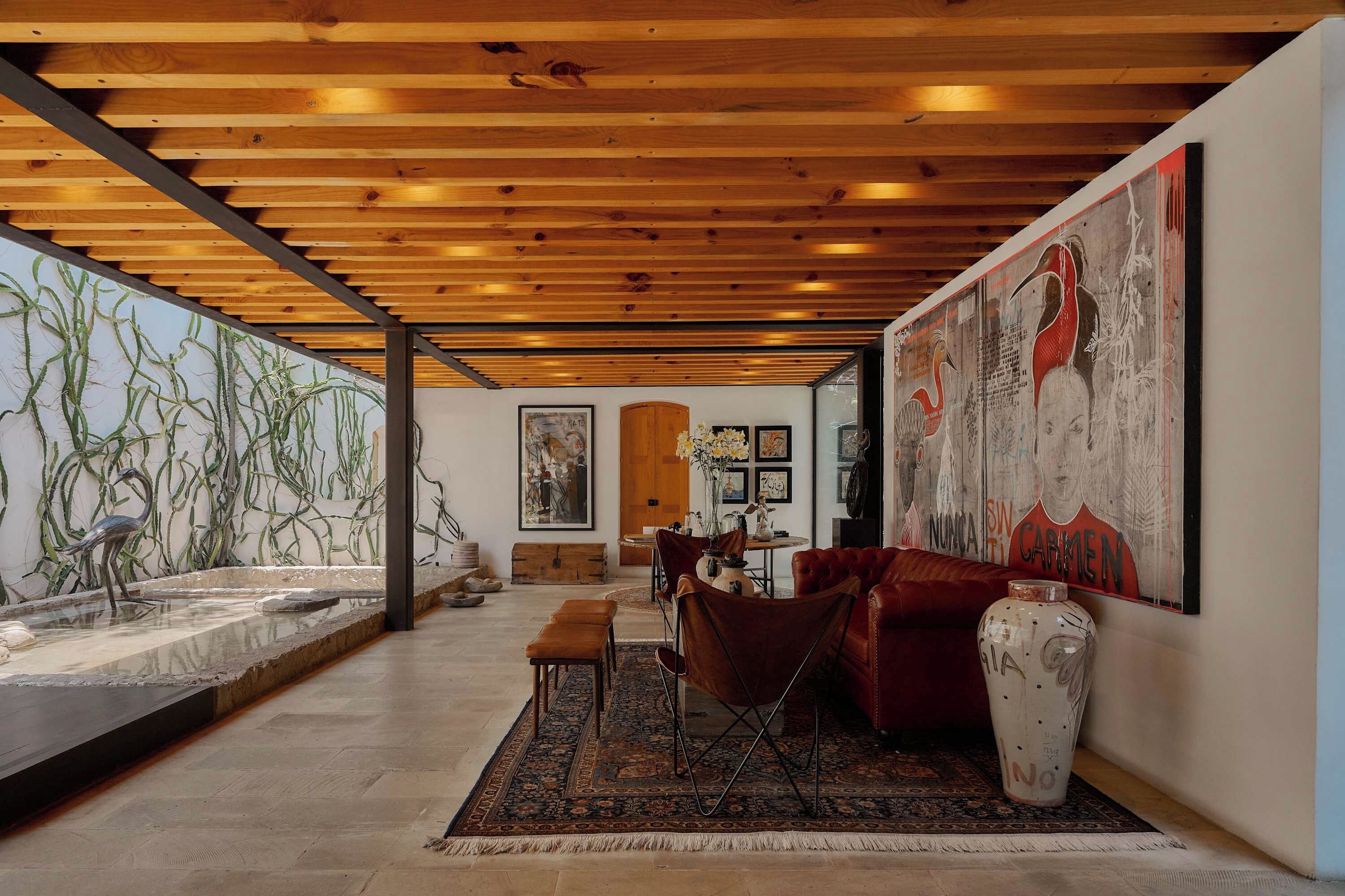 A spacious room with a wooden ceiling, a large painting, a dining area, and a water feature.