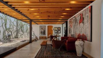 A spacious room with a wooden ceiling, a large painting, a dining area, and a water feature.