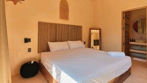 Een slaapkamer met een groot bed, nachtkastje, spiegel en kledingkast.