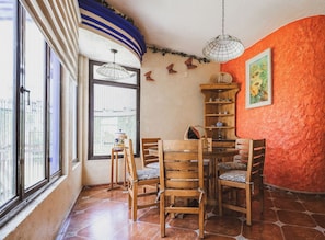 Un coin repas avec une table ronde et des chaises, une fenêtre donnant sur un beau paysage et un mur orné d’un tableau.