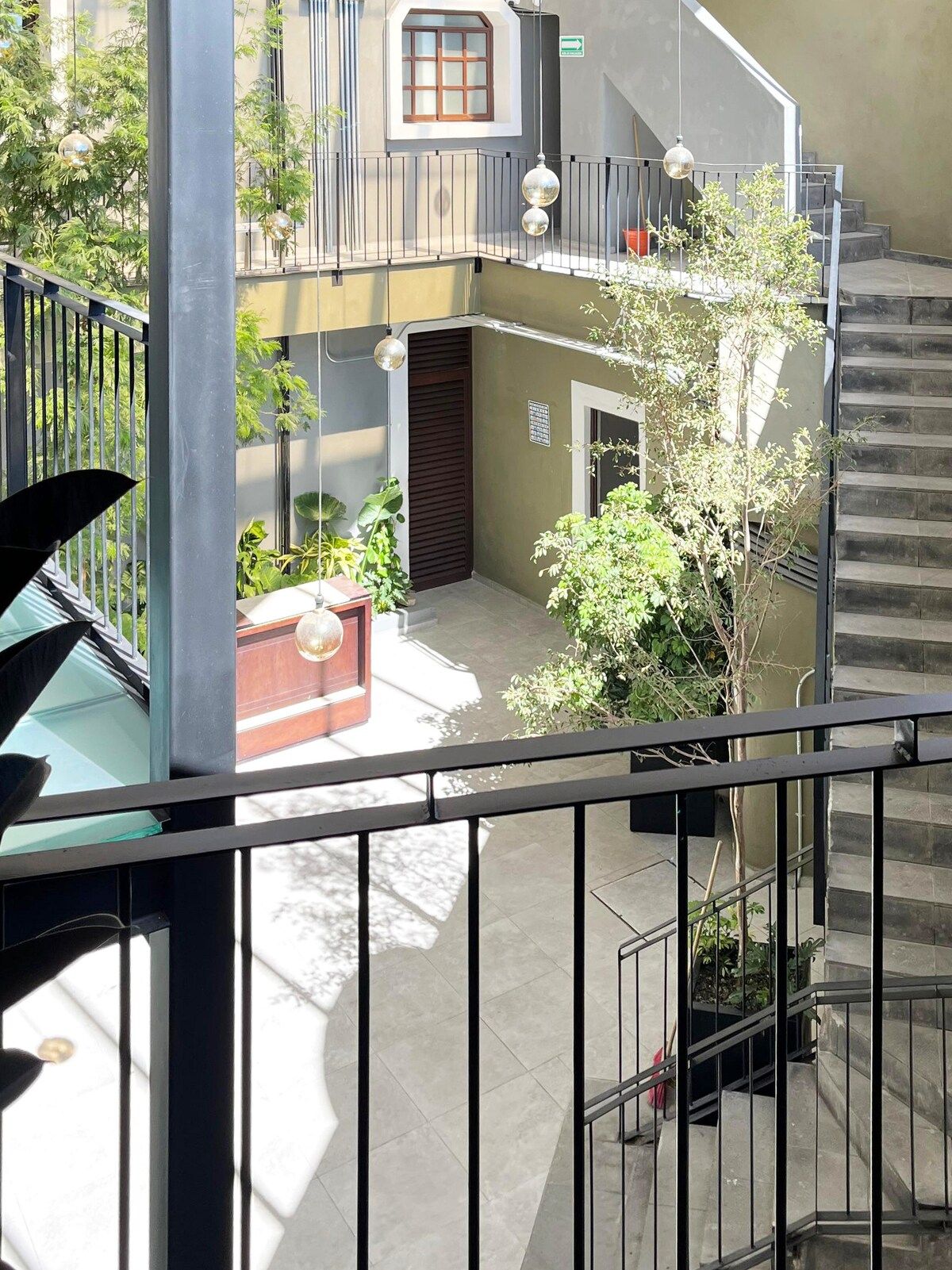 A multi-level building with a staircase, outdoor seating area, and potted plants.