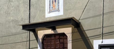 A building facade with a decorative tile, a brown door, and a yellow curb.