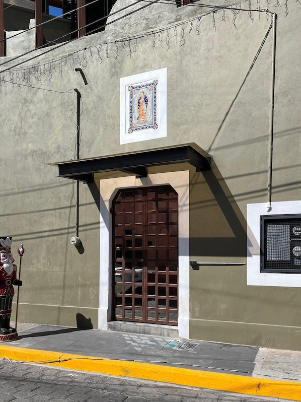 A building facade with a decorative tile, a brown door, and a yellow curb.