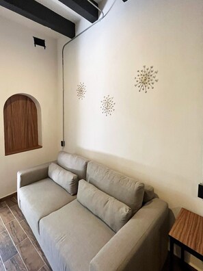 A neutral-toned sofa in a room with a simple, clean design, a small wooden table, and a wall-mounted decorative element.