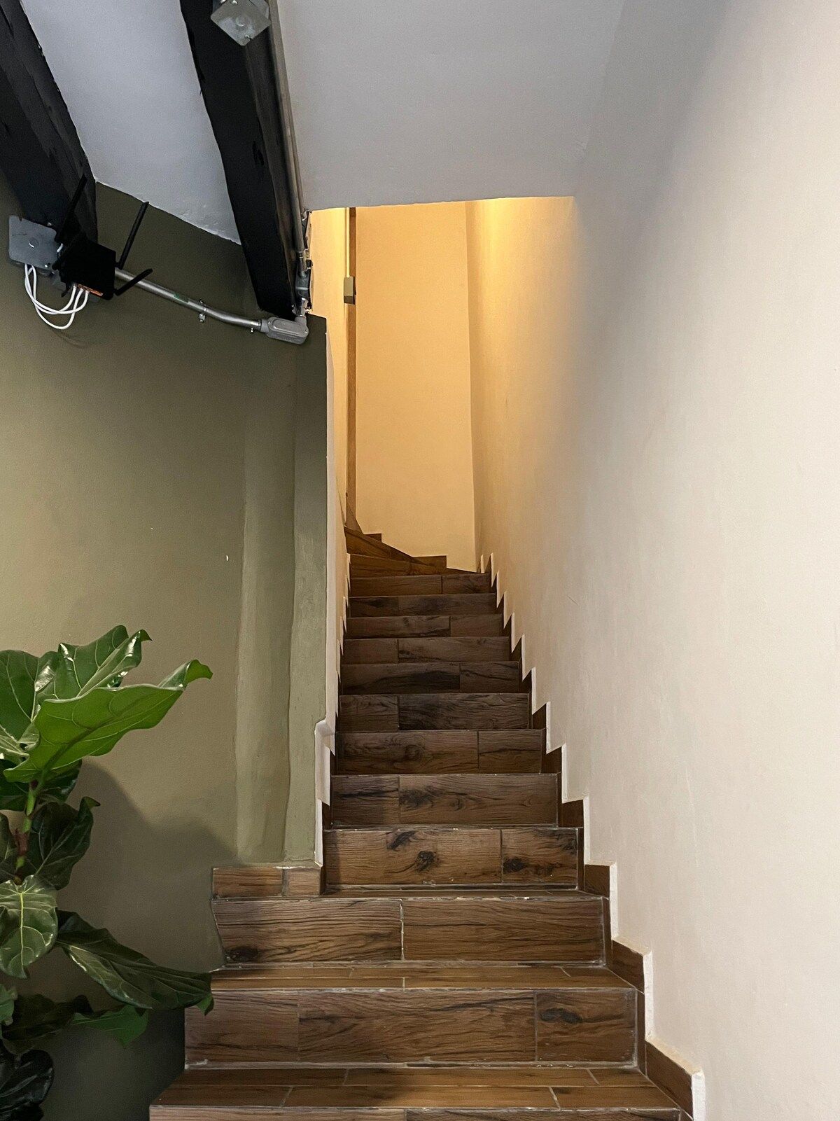A wooden staircase with a handrail, leading to a landing with a light fixture.