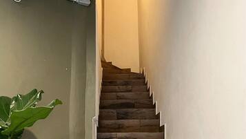 A wooden staircase with a handrail, leading to a landing with a light fixture.