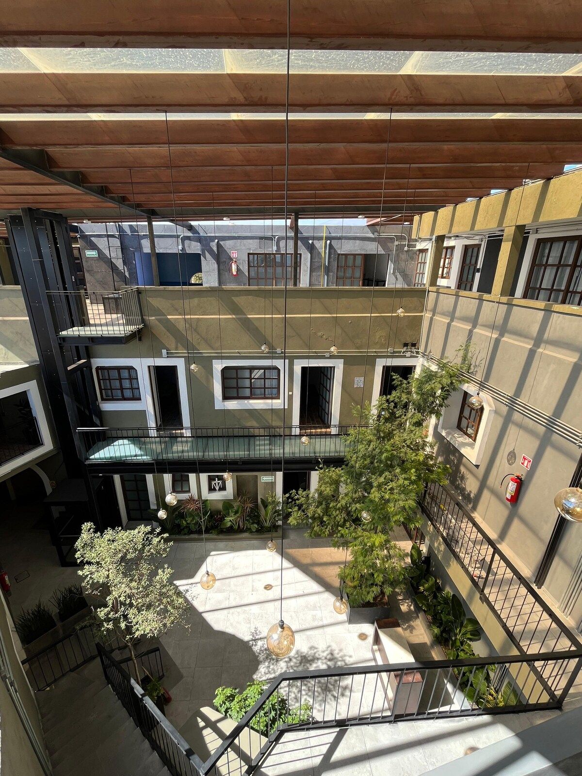 Pátio em vários níveis com um espaço aberto central, rodeado por edifícios com varandas e janelas.