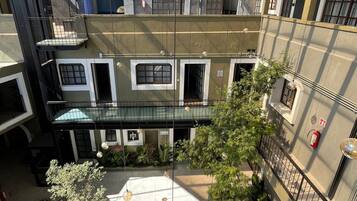 Pátio em vários níveis com um espaço aberto central, rodeado por edifícios com varandas e janelas.