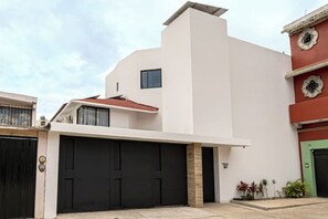 Ein modernes, zweistöckiges Haus mit Garage, kleinem Fenster und einer Tür mit dekorativem Wappen.