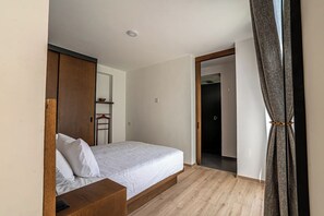 Ein Schlafzimmer mit einem Bett, einem Holzkopfende und einer Tür zu einem anderen Raum.