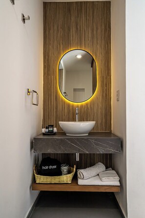 Um banheiro moderno com uma pia independente, um espelho com iluminação circular e um porta-toalhas.