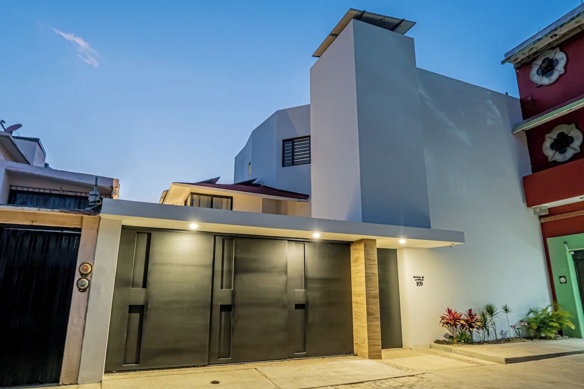 Un bâtiment moderne doté d’un grand portail de garage, d’une enseigne indiquant clairement l’adresse et d’un petit jardin agrémenté de plantes.